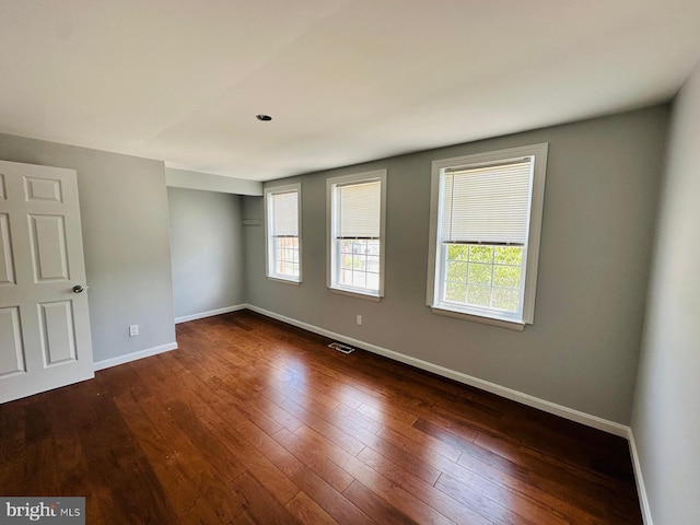 empty room with plenty of natural light and dark wood-type flooring