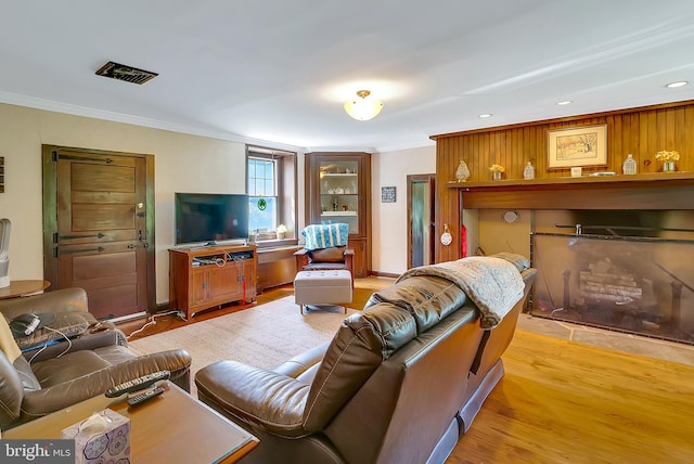 living room featuring crown molding and light hardwood / wood-style flooring