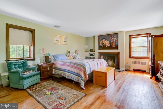 bedroom with radiator heating unit and light hardwood / wood-style flooring