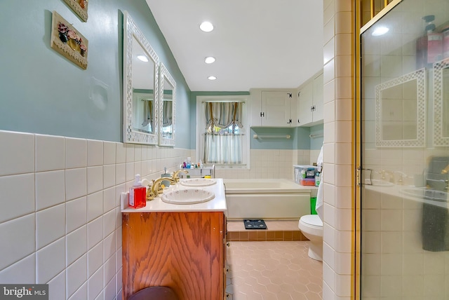 full bathroom with tile patterned floors, vanity, tile walls, independent shower and bath, and toilet