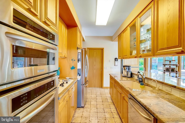 kitchen with light stone countertops, sink, and stainless steel appliances