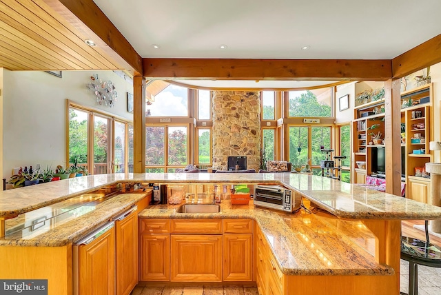 kitchen with light stone countertops, sink, a kitchen breakfast bar, a fireplace, and a kitchen island