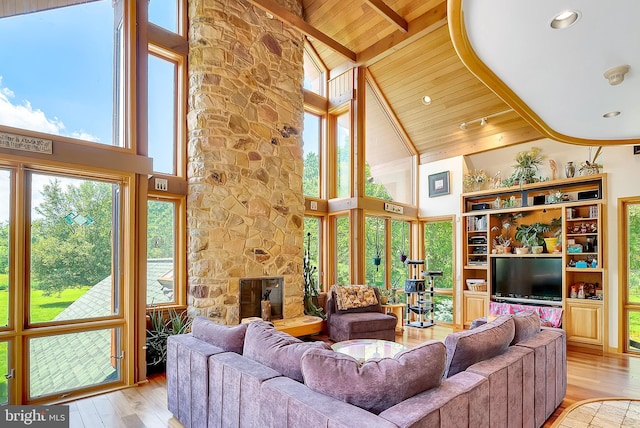 living room featuring beam ceiling, wooden ceiling, light hardwood / wood-style flooring, high vaulted ceiling, and a fireplace