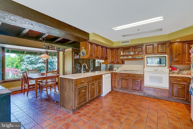 kitchen with light tile patterned flooring, white appliances, decorative light fixtures, and sink