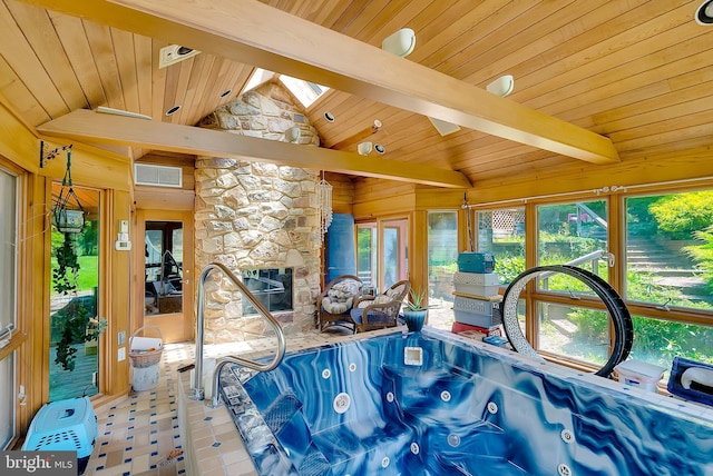 interior space with vaulted ceiling with beams, a stone fireplace, plenty of natural light, and wooden ceiling