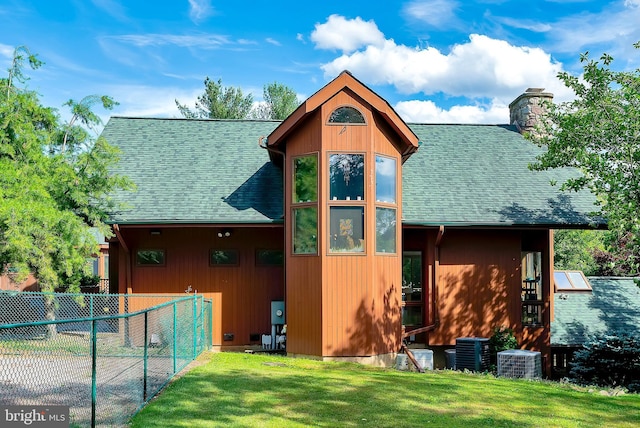 back of property with central AC unit and a lawn