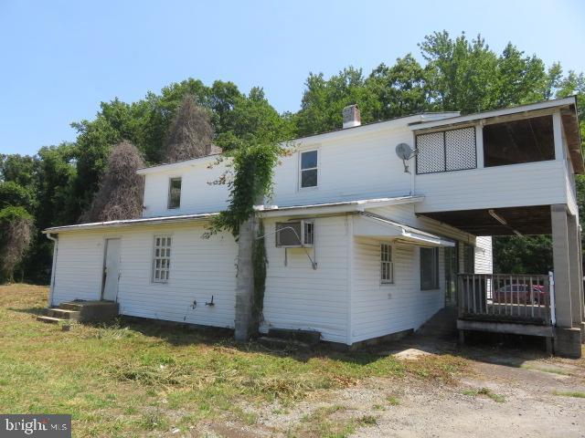 rear view of house with a yard and a wall unit AC