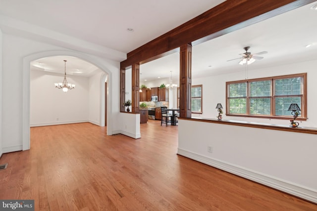 empty room featuring ceiling fan with notable chandelier and light wood-type flooring