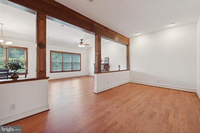 unfurnished living room featuring ceiling fan with notable chandelier and light hardwood / wood-style floors