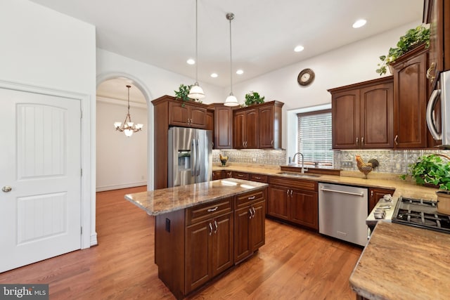 kitchen featuring sink, light hardwood / wood-style floors, pendant lighting, a kitchen island, and appliances with stainless steel finishes