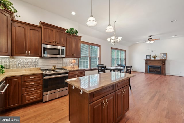 kitchen featuring decorative backsplash, ceiling fan with notable chandelier, stainless steel appliances, decorative light fixtures, and light hardwood / wood-style floors