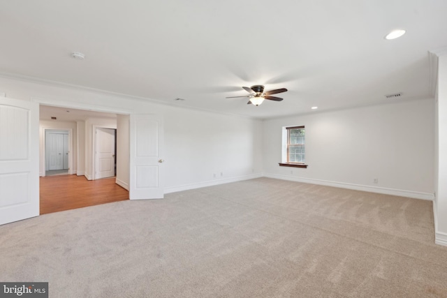 empty room featuring crown molding, ceiling fan, and light colored carpet