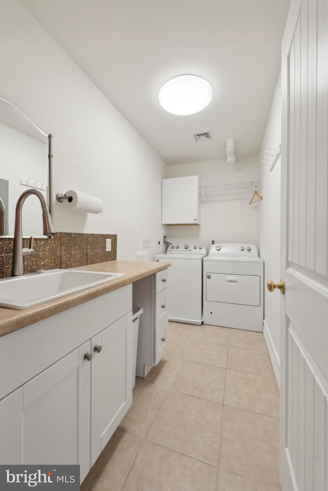 clothes washing area featuring cabinets, separate washer and dryer, sink, and light tile patterned floors