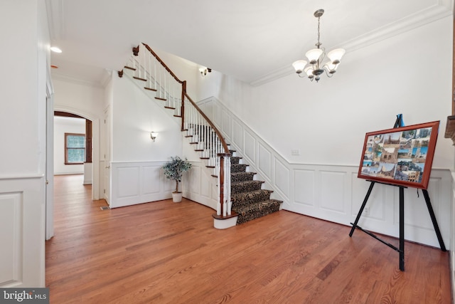 interior space featuring hardwood / wood-style floors, an inviting chandelier, and ornamental molding