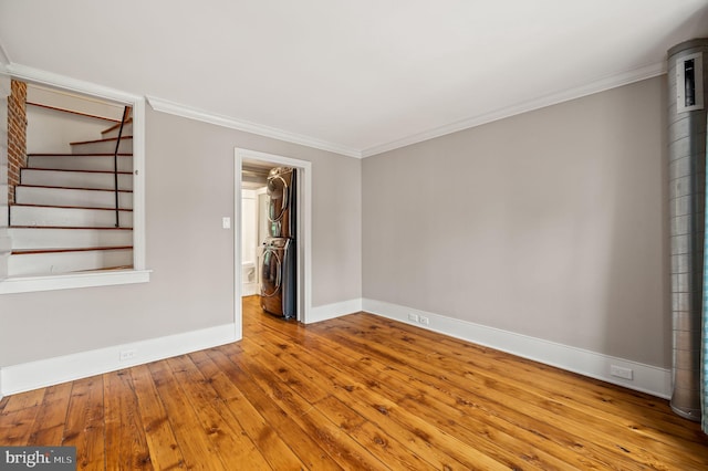 spare room featuring stacked washer and dryer, light hardwood / wood-style floors, and crown molding