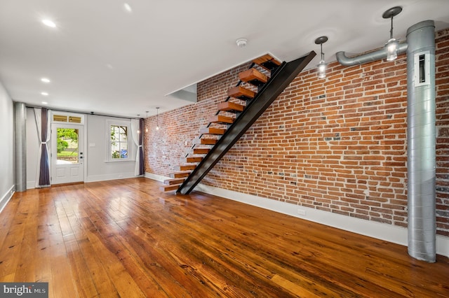 unfurnished living room with hardwood / wood-style flooring and brick wall