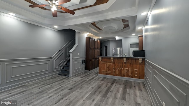 kitchen with kitchen peninsula, stainless steel fridge, crown molding, and light hardwood / wood-style flooring