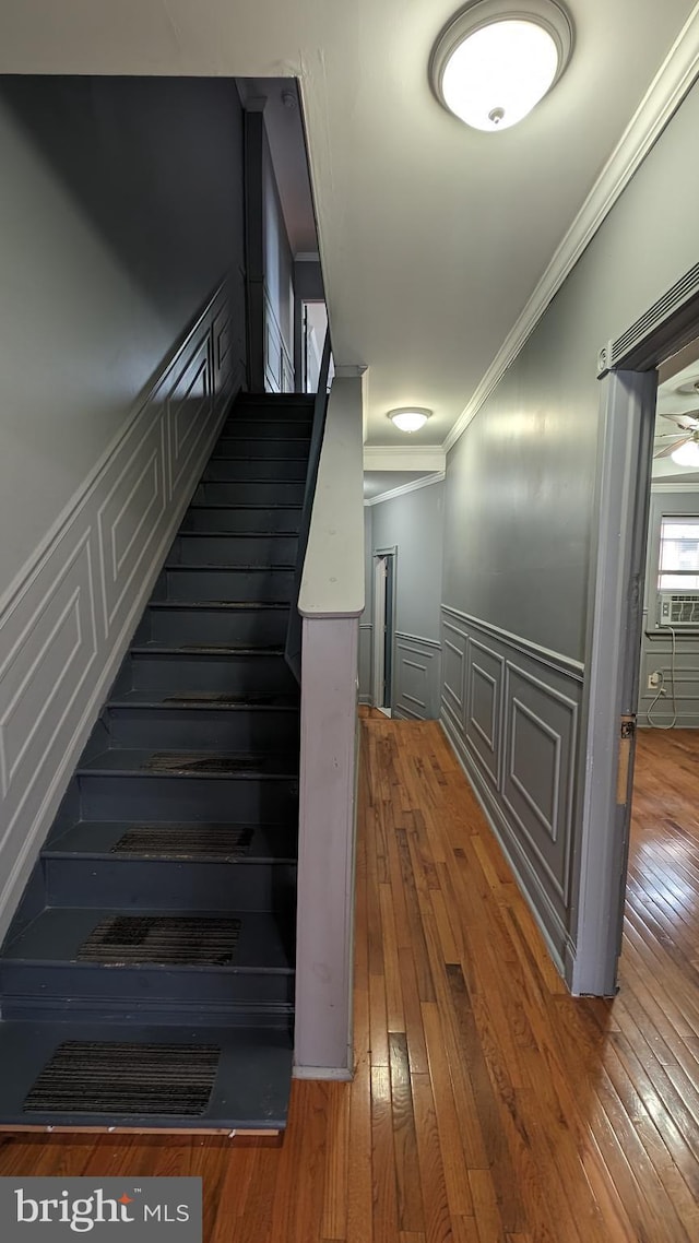 stairs featuring cooling unit, ornamental molding, and hardwood / wood-style flooring