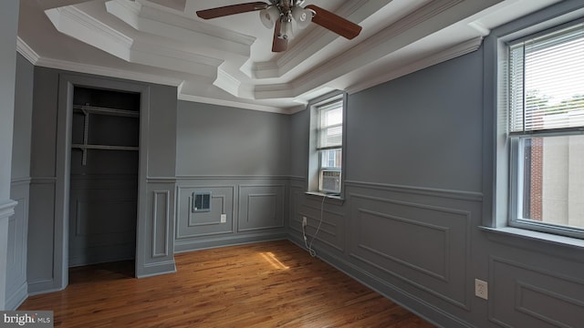 spare room featuring a raised ceiling, crown molding, dark hardwood / wood-style flooring, and ceiling fan