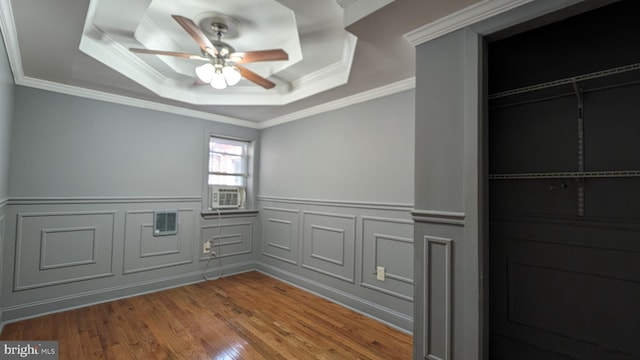 empty room featuring a tray ceiling, ceiling fan, wood-type flooring, and ornamental molding