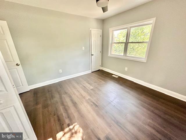 unfurnished room with dark hardwood / wood-style flooring and ceiling fan