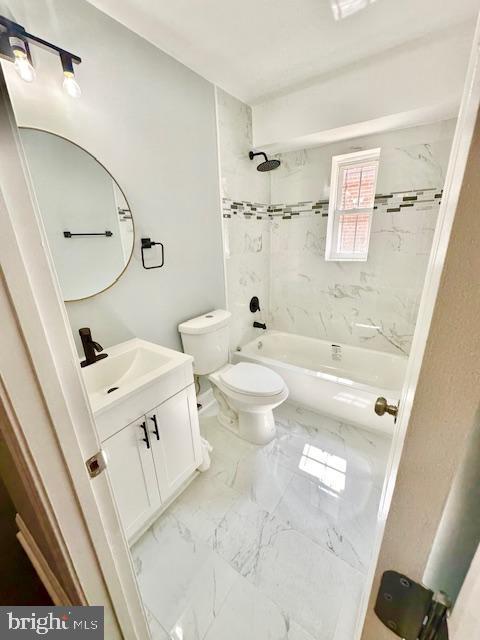 full bathroom featuring vanity, tiled shower / bath combo, and toilet