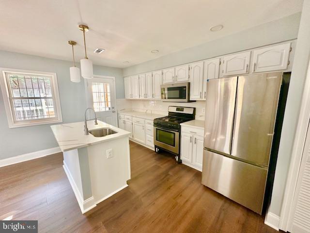 kitchen with pendant lighting, stainless steel appliances, white cabinetry, and sink