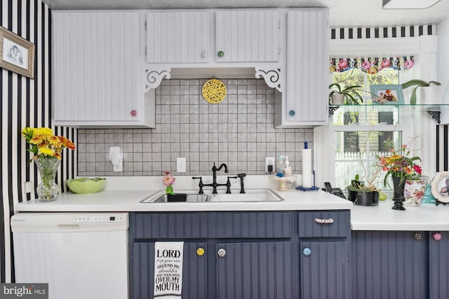 kitchen featuring white cabinets, sink, blue cabinetry, dishwasher, and decorative backsplash