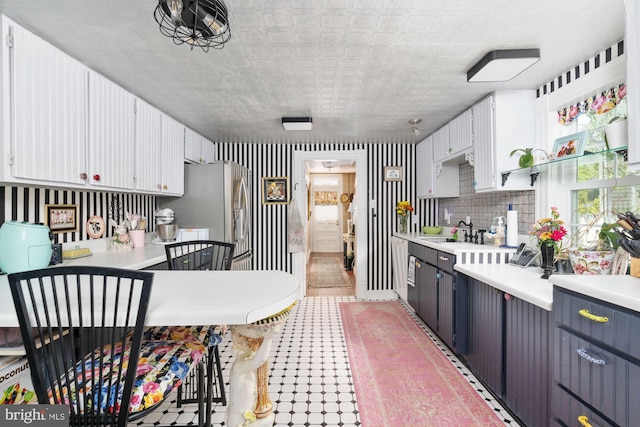 kitchen featuring backsplash, white cabinetry, sink, and stainless steel fridge