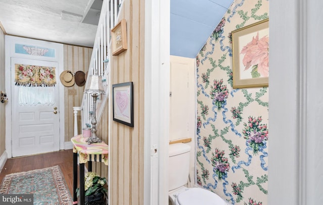 interior space with a textured ceiling, hardwood / wood-style floors, lofted ceiling, and toilet