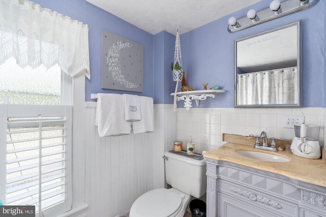 bathroom with tile walls, vanity, and toilet