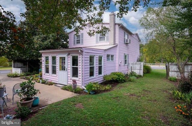 rear view of house featuring cooling unit, a lawn, and a patio