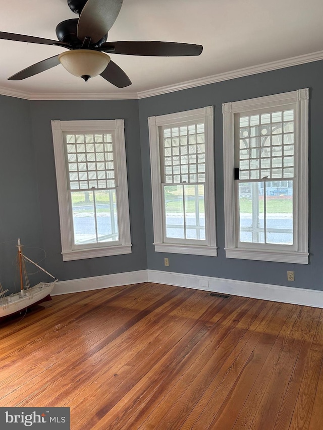 unfurnished room with ceiling fan, a healthy amount of sunlight, wood-type flooring, and crown molding