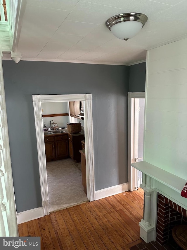 hall featuring light hardwood / wood-style floors, ornamental molding, and sink