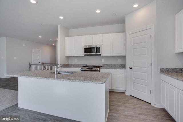 kitchen with sink, white cabinetry, stainless steel appliances, and a kitchen island with sink