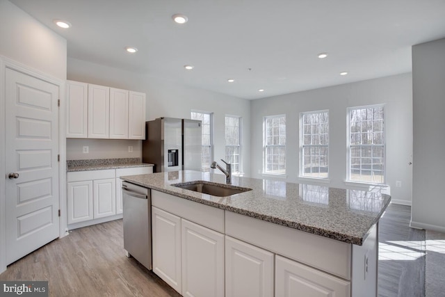 kitchen with white cabinets, sink, light hardwood / wood-style flooring, an island with sink, and stainless steel appliances