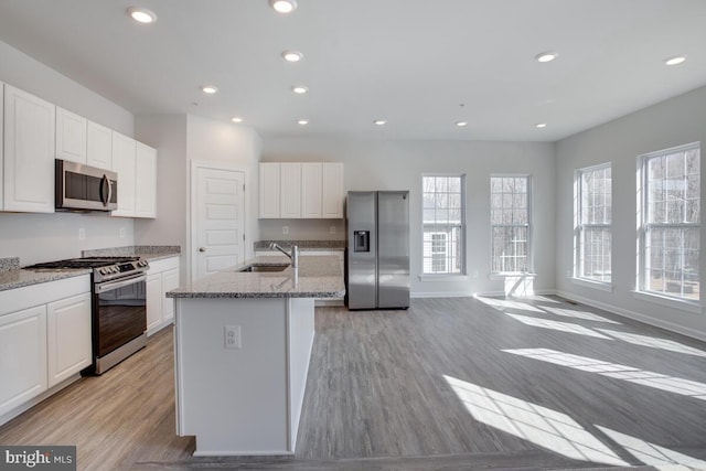 kitchen featuring white cabinets, a kitchen island with sink, sink, and appliances with stainless steel finishes