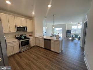 kitchen with kitchen peninsula, stainless steel appliances, white cabinetry, and dark wood-type flooring