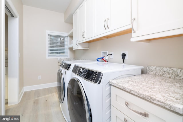 washroom with cabinets, light hardwood / wood-style flooring, and washer and dryer