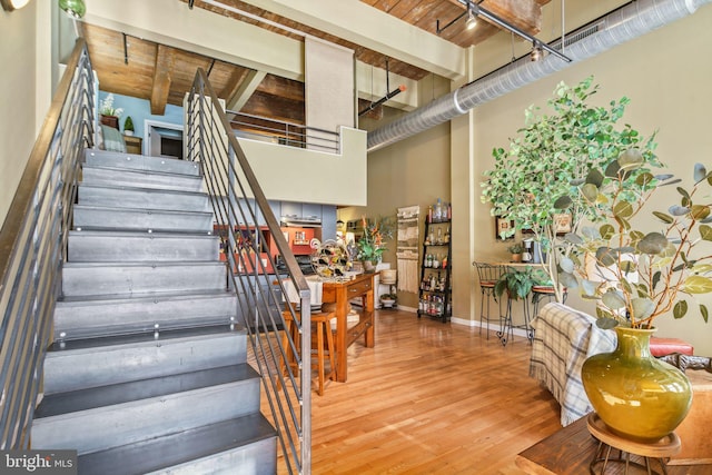 stairs with beamed ceiling, wooden ceiling, and hardwood / wood-style flooring