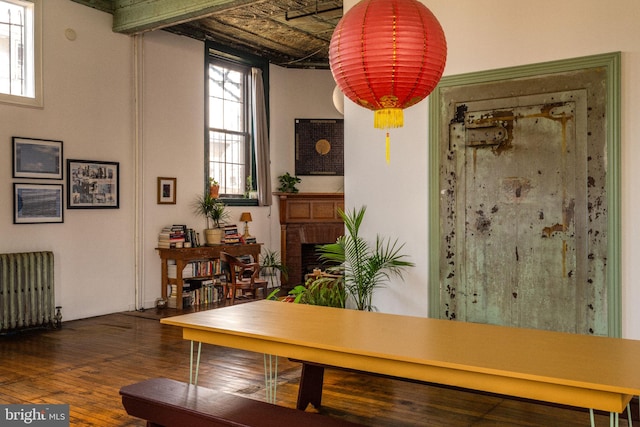 dining space with hardwood / wood-style floors, a brick fireplace, and radiator