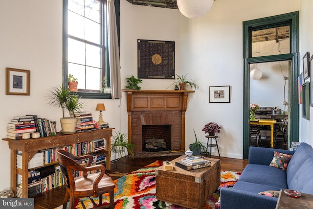 living room featuring wood-type flooring and a brick fireplace