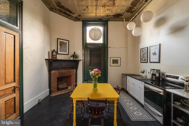 kitchen featuring sink, a brick fireplace, dark hardwood / wood-style floors, stainless steel range with electric cooktop, and white cabinets