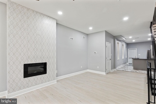 unfurnished living room with a tile fireplace and light wood-type flooring