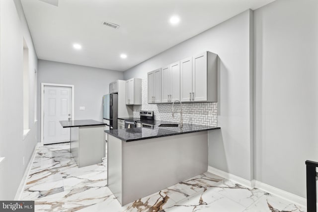 kitchen with sink, a center island, kitchen peninsula, dark stone counters, and appliances with stainless steel finishes