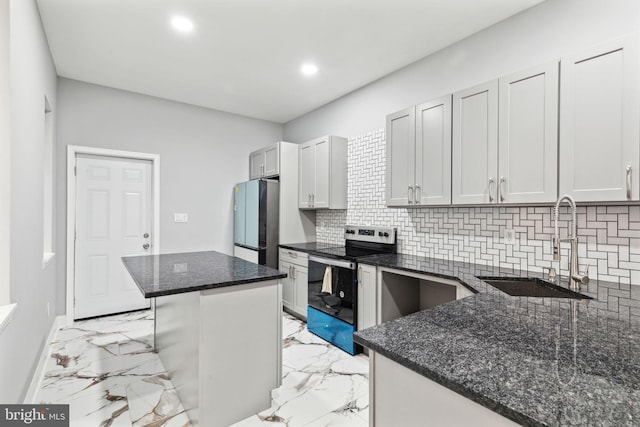 kitchen featuring a kitchen bar, stainless steel appliances, sink, dark stone countertops, and a center island