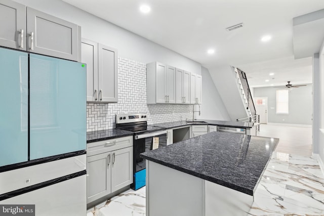 kitchen with stainless steel range with electric stovetop, dark stone counters, refrigerator, sink, and ceiling fan