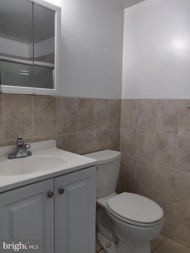 bathroom with tile patterned floors, vanity, toilet, and tile walls