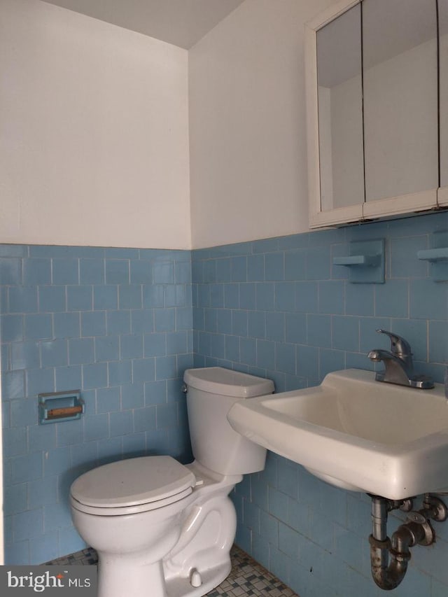 bathroom featuring tile patterned floors, sink, tile walls, and toilet