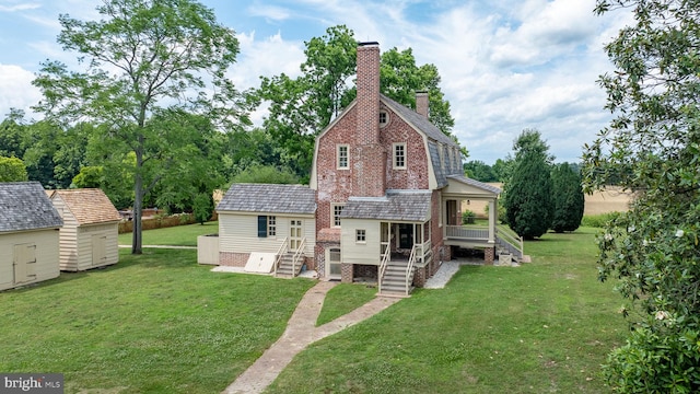 rear view of house with a shed and a yard